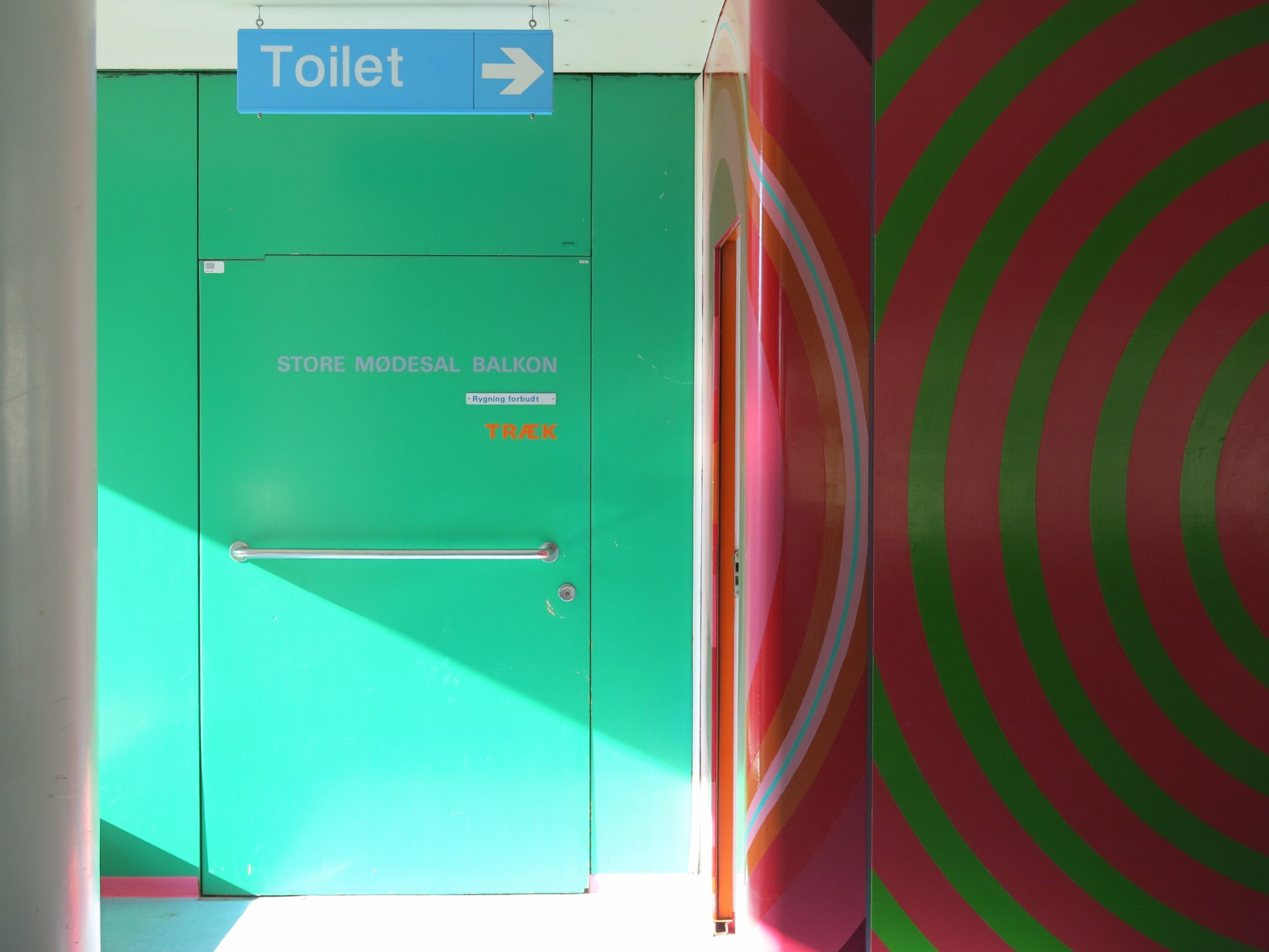a green door, a blue toilet sign and a red wall