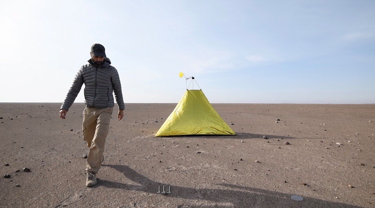 man walking away from tent in desert